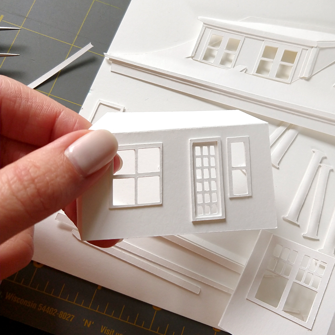 a hand holding a model of a house