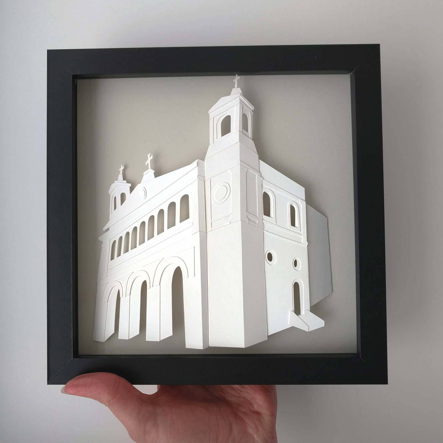 a hand holding a paper cut of a church