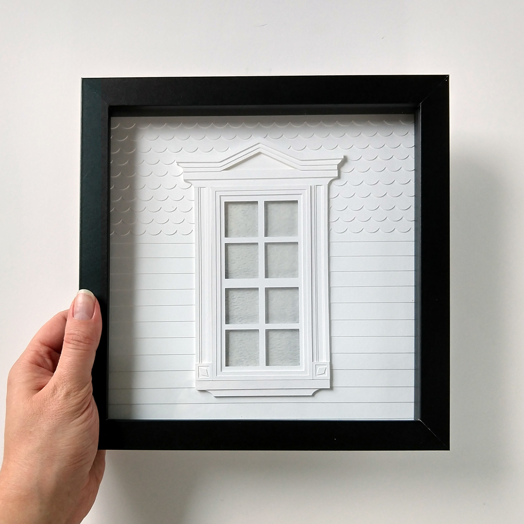 a hand holding a black and white frame with a window