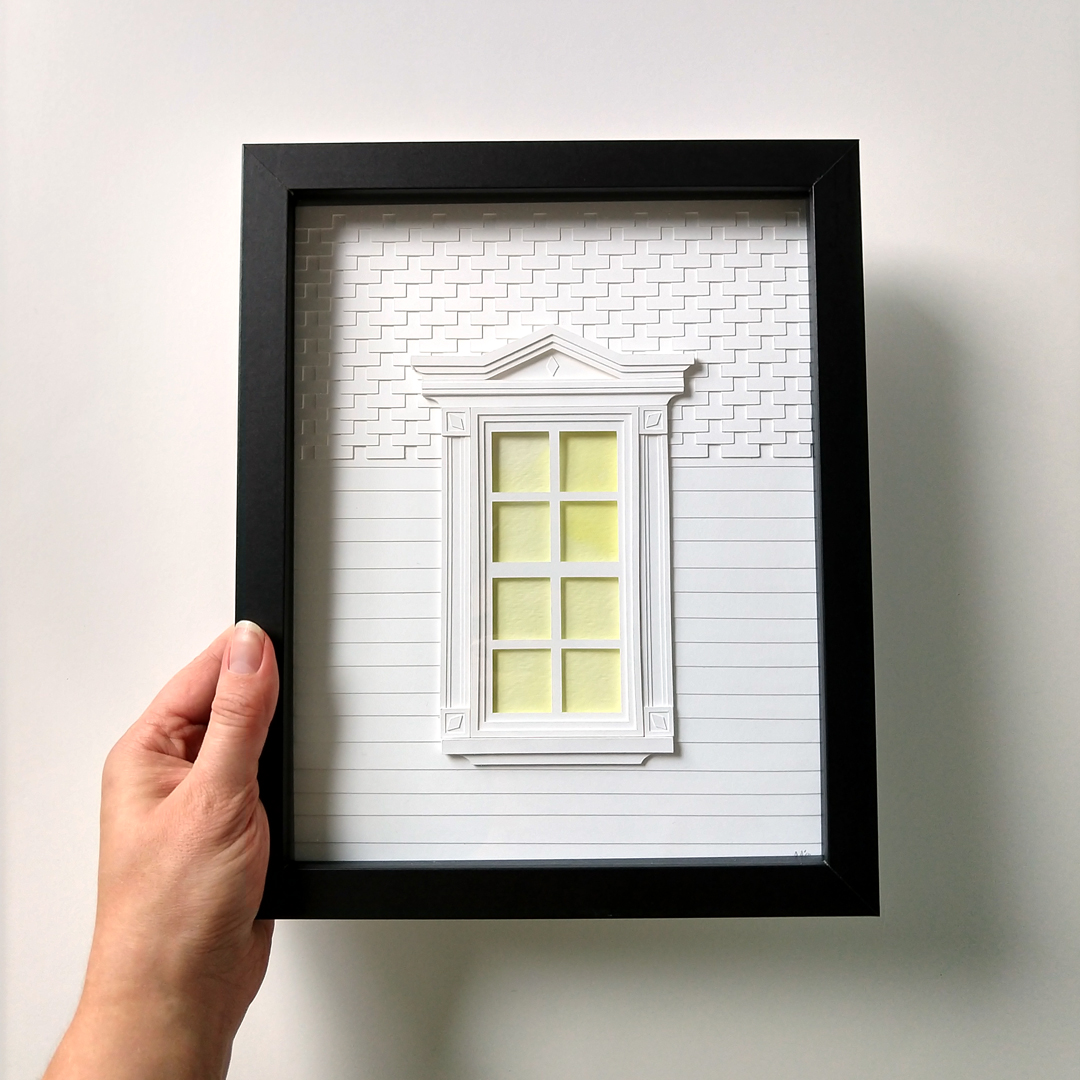 a hand holding a paper model of a window
