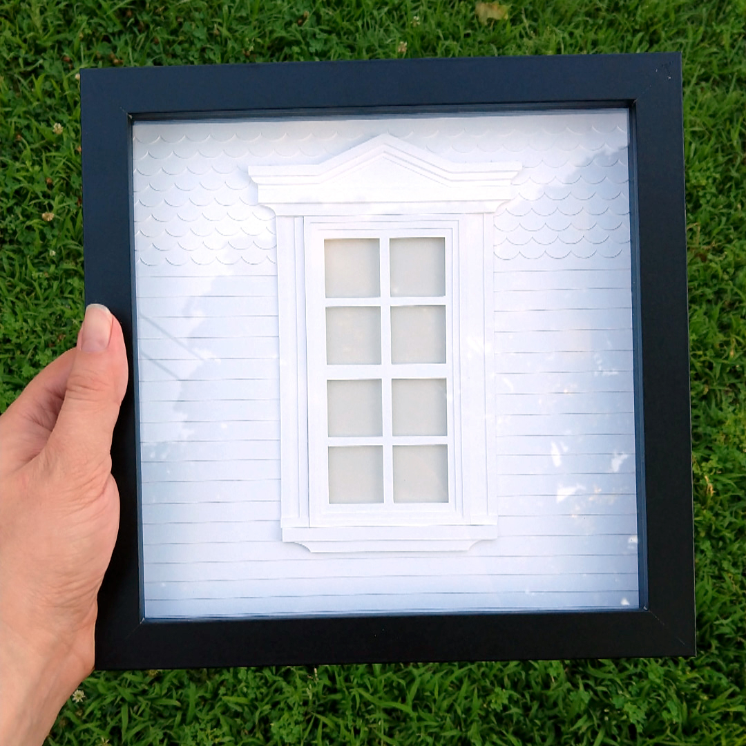 a person holding a shadow box with a window in it