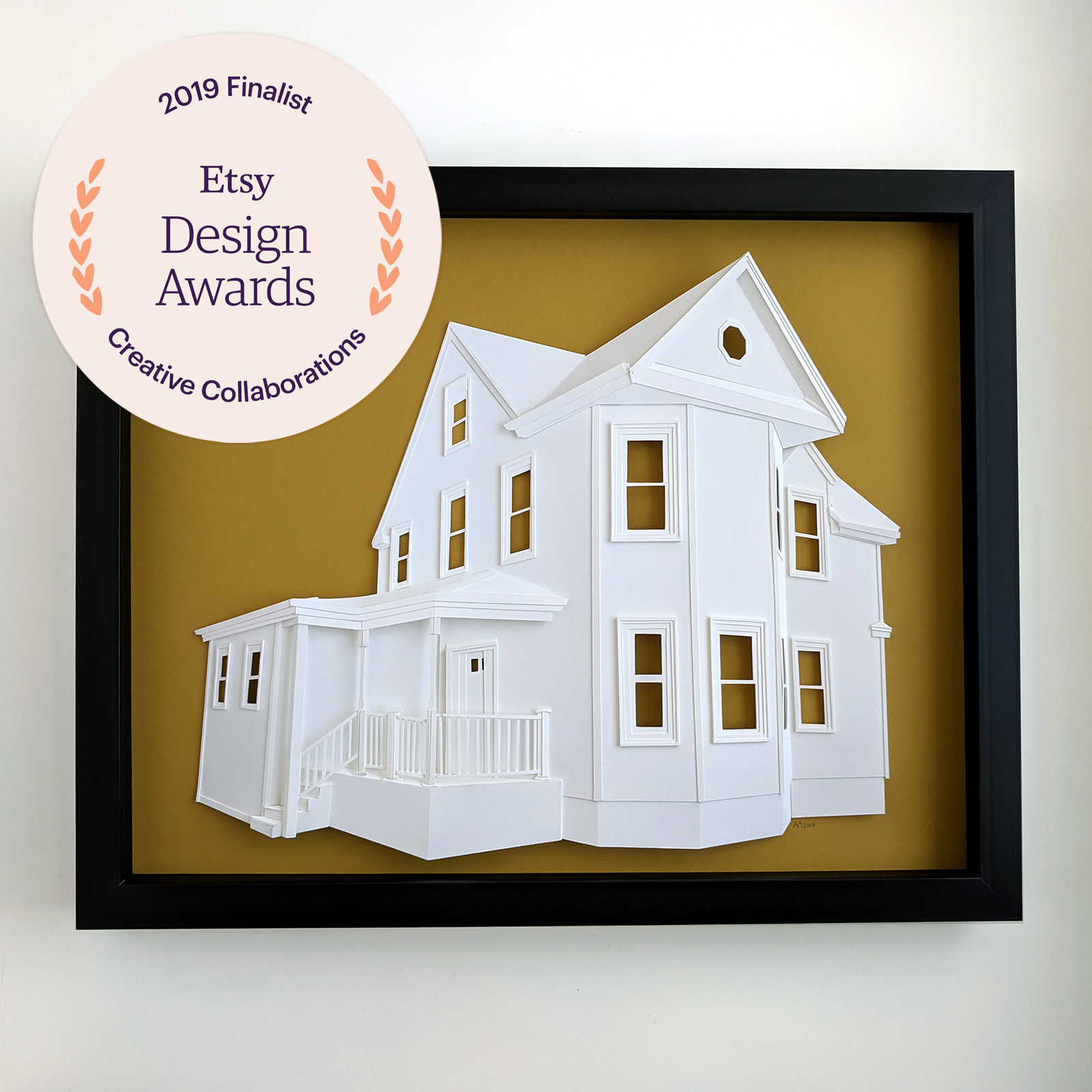 Custom house portrait made of paper depicting a large house with a deep front porch, overlaid with the Etsy Design Awards Creative Collaborations Finalist logo