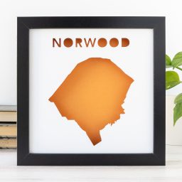 a framed poster with the shape of Norwood, MA cut out to reveal an orange background