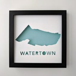 a black frame holding a paper cut out of watertown