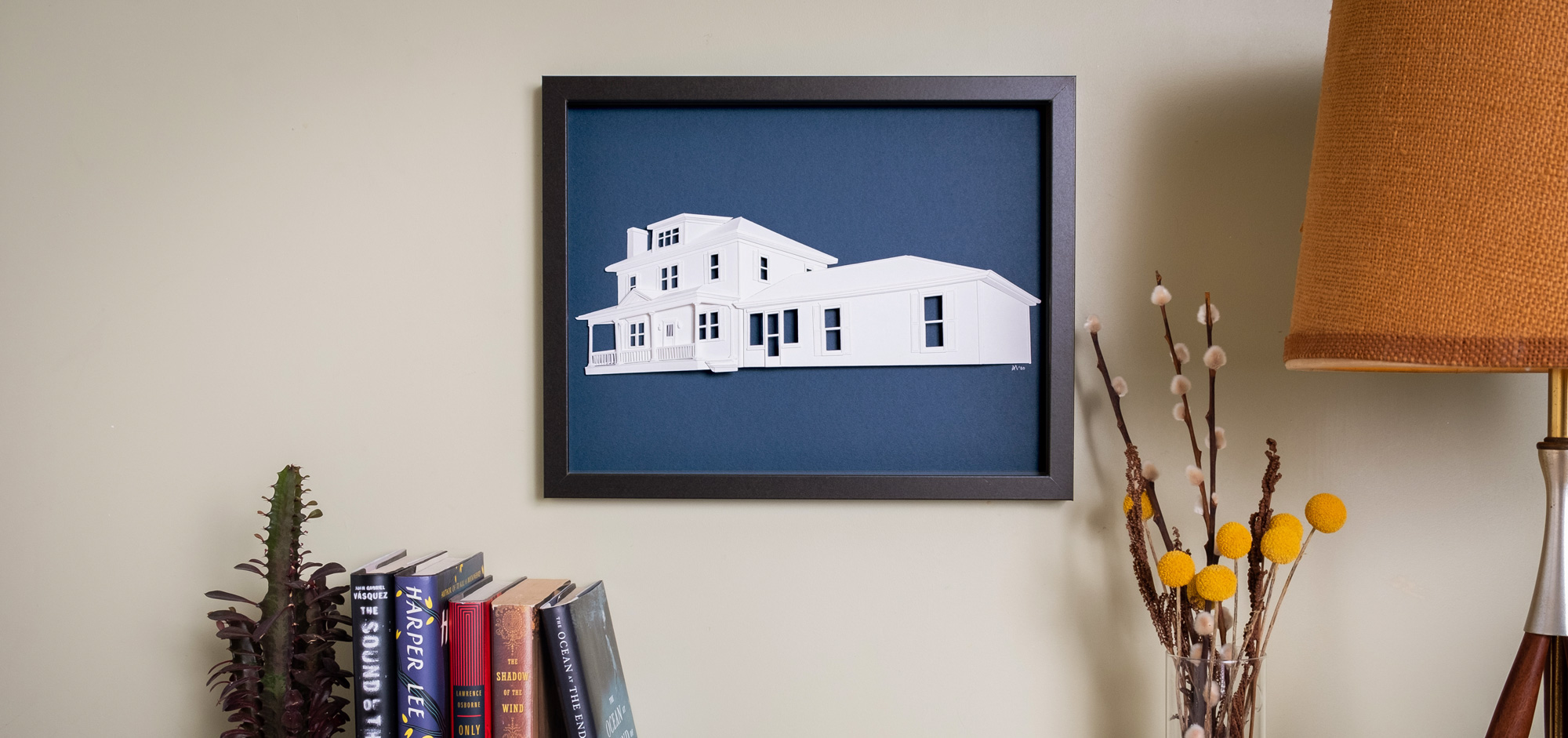 Framed house portrait hanging on a living room wall