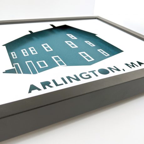 Framed house portrait silhouette depicting a three-story duplex home with the label "Arlington, MA" underneath, white and teal artwork in a black frame