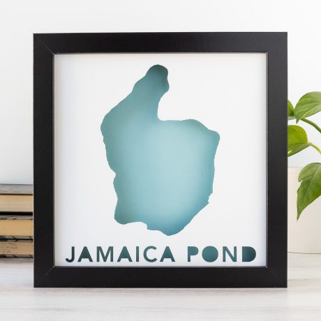 A black frame with a blue silhouette of Jamaica Pond cut out of white paper